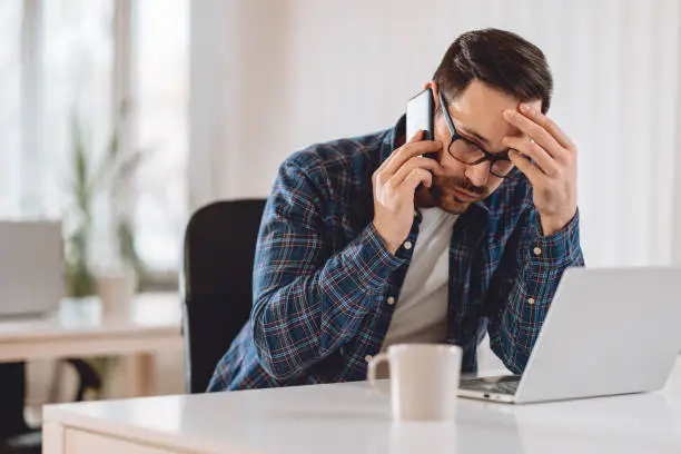 Worried businessman talking on phone in the office