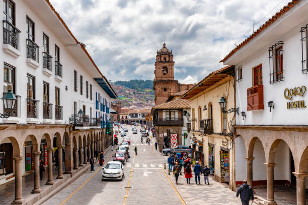 Cusco, Peru - April 3, 2019: View at the traffic on the street with old colonial buildings and Plaza de Armas with a church at the background in Cusco, Peru.