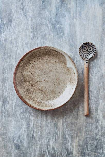 istock Empty ceramics plate and spoon on rustic wooden background. Top view. Copy space. 1218456196