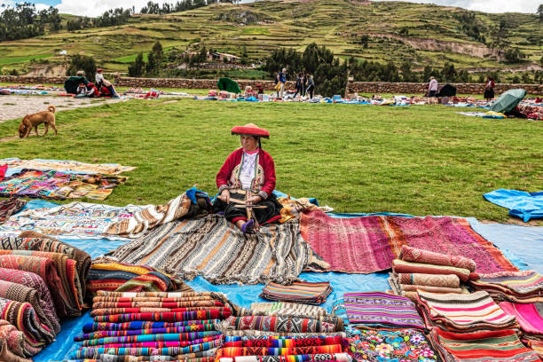 Textile products on sale in Chinchero street of Urubamba Province in Peru. Chinchero, Peru – April 4, 2019: Local woman selling traditional Peruvian textile handicraft and knits products made of Alpaca wool at the central Plaza in Chinchero, Peru. chinchero district stock pictures, royalty-free photos & images