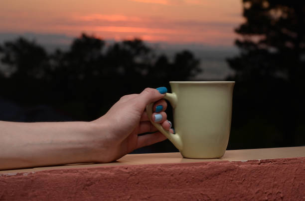 istock Female hand holding white mug on sunset background. Copy space mock up 1218462477