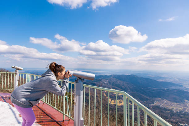 istock Young woman looking at view of landscape using binoculars 1218463167