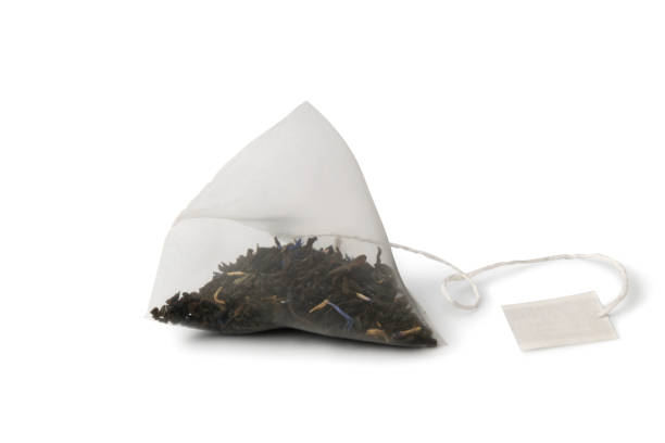 白い背景に分離された黒アールグレーティーとクローズアップピラミ�ッドティーバッグ - herbal medicine tea crop tea leaves dry ストックフォトと画像