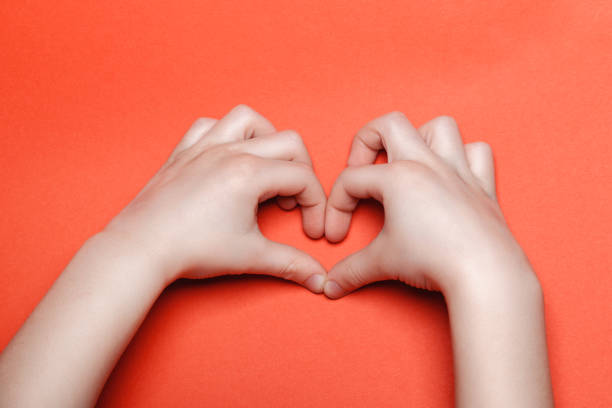 istock Child make a heart on a red background 1218467972