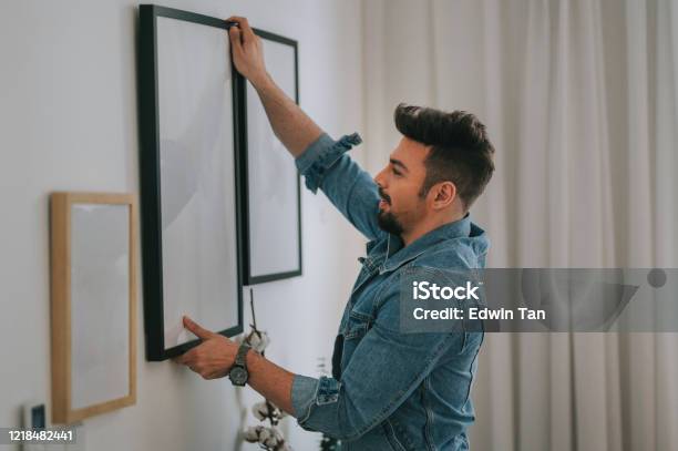 Ein Mann Aus Dem Mittleren Osten Mit Bart Der Ein Gemälde An Der Wand Seines Wohnzimmers Hängt Stockfoto und mehr Bilder von Gemälde