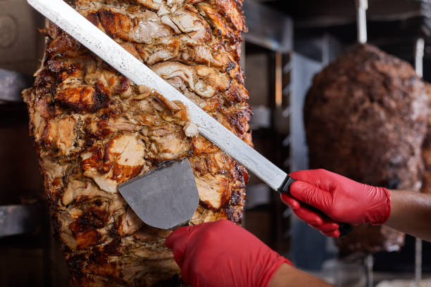 Fried meat on a skewer for cooking of donors or shawarma. Close-up Fried meat on a skewer for cooking of donors or shawarma. Hands close-up cuts meat in thin slice shawarma stock pictures, royalty-free photos & images
