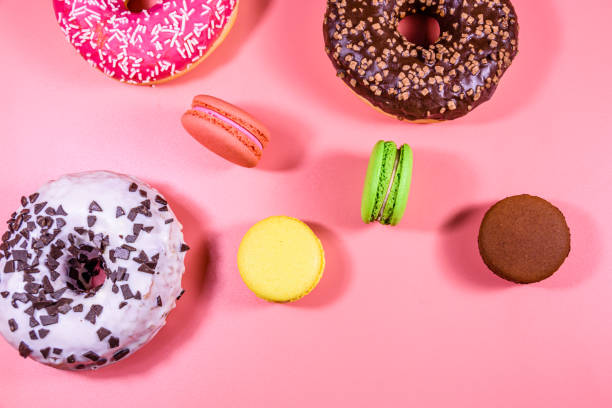 istock Fresh glazed donuts and french macaroons isolated on a pink background 1218487032