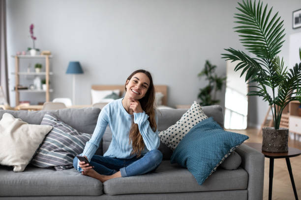 istock Smiling woman using mobile on the sofa at home. Online chat. 1218492701