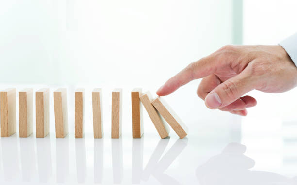 istock Man hand pushing domino pieces 1218493408