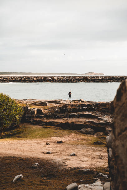 наслаждаясь восходом солнца на скалистом краю воды, ямба - hiking coastline waters edge sunny стоковые фото и изображения