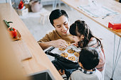 istock Father and kids baking cookies together in the kitchen and smelling freshly baked cookies straight from the oven. Stay at home self isolation during the Covid-19 health crisis 1218496575
