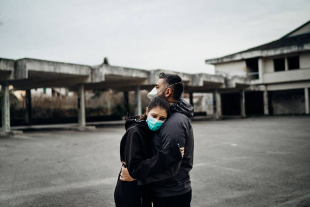 Two people in masks hugging.Couple being divided by incurable infectious disease.Infection control,isolation.Loved one illness.Saying goodbye.Farewell.Letting go.Toxic relationship. stock photo