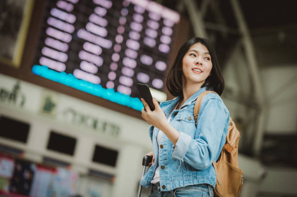 istock Asian woman traveller using smartphone at train station terminal 1218501508