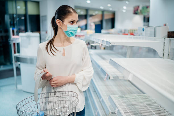 Shopping during the epidemic.Buyer wearing a protective mask.Panic buying during coronavirus outbreak.Deficiency in drugstores and pharmacies during an emergency lockdown.Sold out household supplies. stock photo