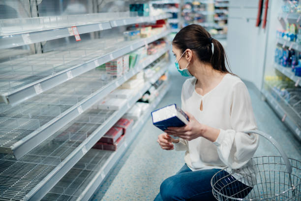 Woman wearing face mask buying in supermarket/drugstore with sold-out supplies.Preparation for a pandemic quarantine due to coronavirus covid-19 outbreak.Hygiene, cleaning and disinfection products. stock photo