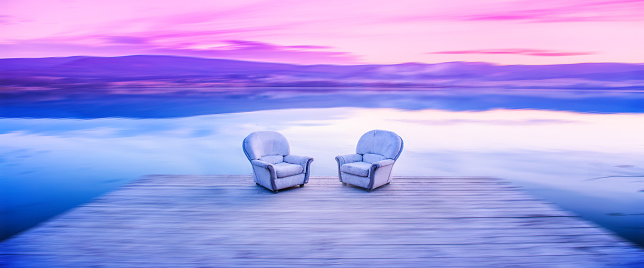 Banner, web page or cover template of Chairs by lake, sunset light in background. Thinking, dialogue, conversation photo. Copy space and panoramic ratio