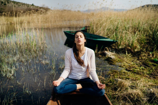 Woman meditating in nature.Escape from stressful reality.Mindful woman practicing meditation.Breathing technique.Mental state issues menagement.Imagination.Traveling with mind.Focus on healing.Stress stock photo