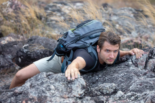 istock hiker man climbing rock on mountain 1218505545