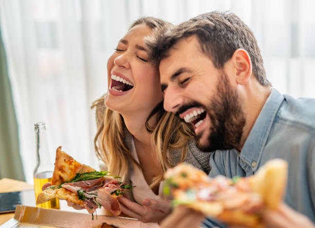 Cheerful couple eating delicious pizza stock photo