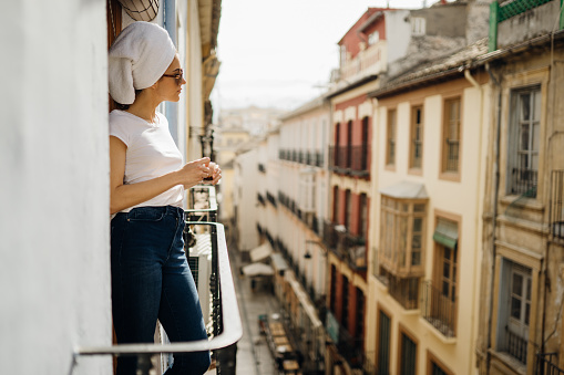 Young european woman spending spa free time home.Self care,staying home.Enjoying view on the balcony.Relaxing at home.Hotel room balcony view,luxury vacation in Europe.Morning ritual.