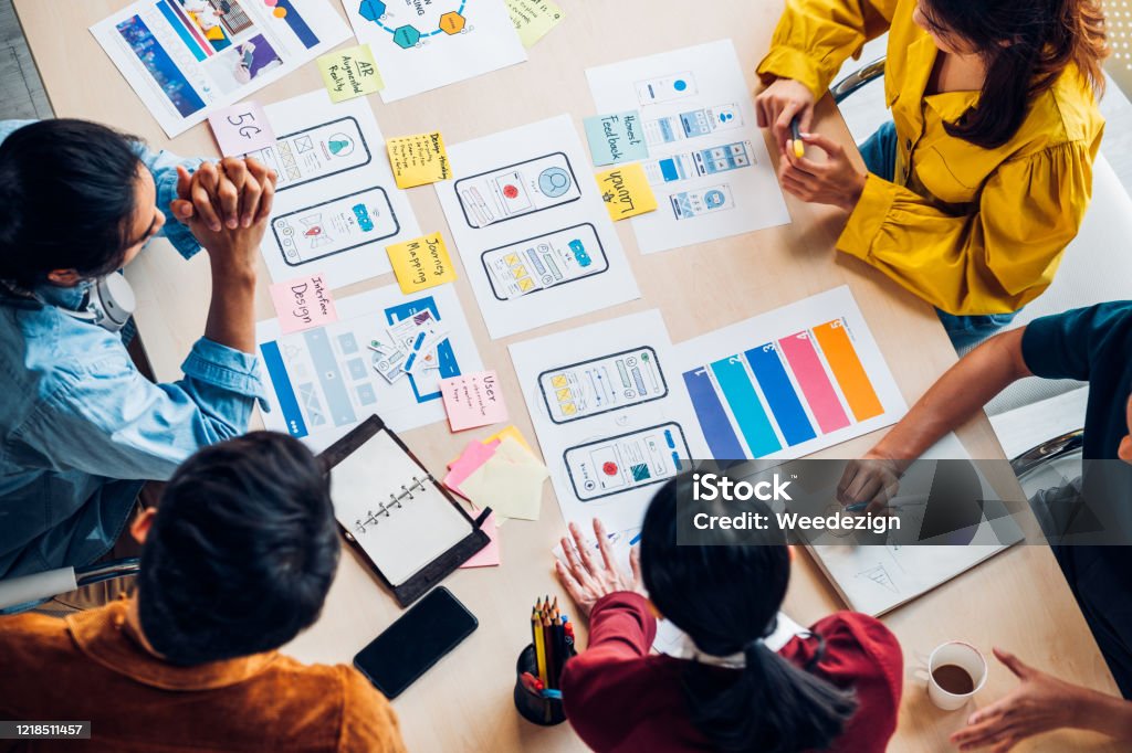 top view asian ux developer and ui designer brainstorming about mobile app interface wireframe design on table with customer brief and color code at modern office.Creative digital development agency Design Stock Photo