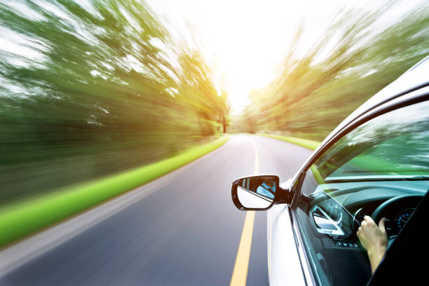 istock Man hand driving a car through a forest 1218512172