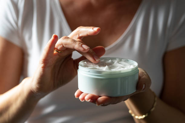 Picking facial cream with finger from a jar Female hands holding a jar of facial cream and picking with finger to apply moisturizing cream stock pictures, royalty-free photos & images