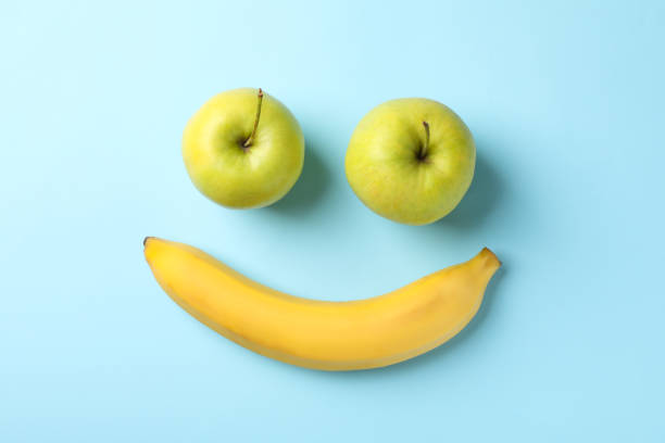 istock Smiley face made of bananas and apples on blue background 1218516772