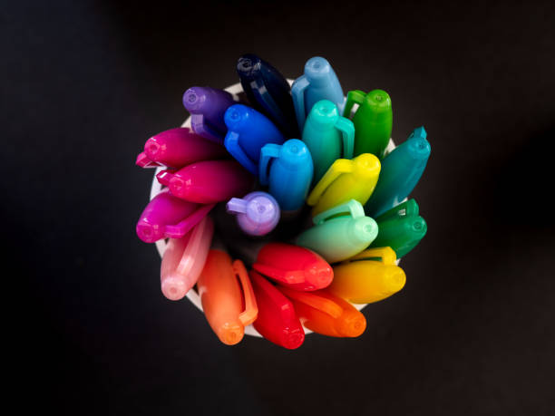 Top down view of colouring pens spiralling in a pot Top down view of colouring pens spiralling in a pot against a black background permanent marker photos stock pictures, royalty-free photos & images