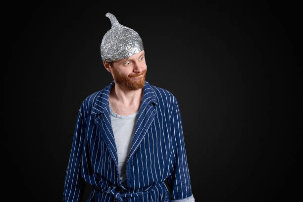 ironic man in foil cap and old holey bathrobe ironic man in foil cap and old holey bathrobe tin foil hat stock pictures, royalty-free photos & images