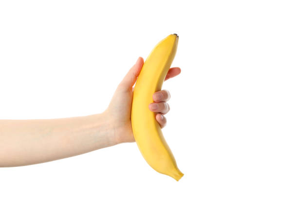 istock Female hand holds banana, isolated on white background 1218518683