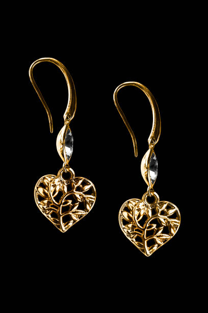 Elegant heart shaped gold carved earrings with crystal isolated over black
