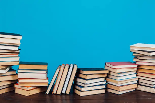 Photo of many stacks of educational books to teach in the library on a blue background