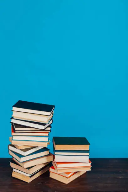 Photo of many stacks of educational books to teach in the library on a blue background