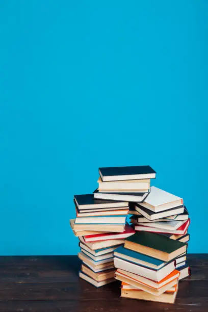 Photo of many stacks of educational books to teach in the library on a blue background