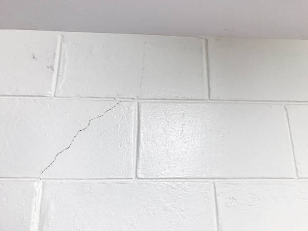 istock The white concrete brick wall cracked. House structure failure. 1218523017