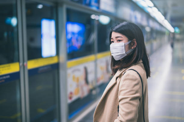 Young asian woman wearing protective face mask stand in line during waiting underground train in subway due to Coronavirus or COVID-19 outbreak situation in all of landmass in the world Young asian woman wearing protective face mask stand in line during waiting underground train in subway due to Coronavirus or COVID-19 outbreak situation in all of landmass in the world landmass stock pictures, royalty-free photos & images
