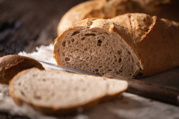 istock Freshly baked bread slice and loaf detail with a knife placed beside on a rustic background. 1218525863