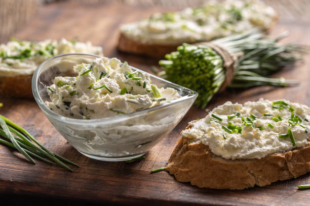 A bowl of homemade cream cheese spread with chopped chives surrounded by bread slices with spread and a bunch of freshly cut chives. A bowl of homemade cream cheese spread with chopped chives surrounded by bread slices with spread and a bunch of freshly cut chives. curd cheese stock pictures, royalty-free photos & images