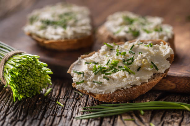 istock Chive cream cheese spread on a bread slices next to bunch of freshly cut chives on a rustic wood and chopping board. 1218526431