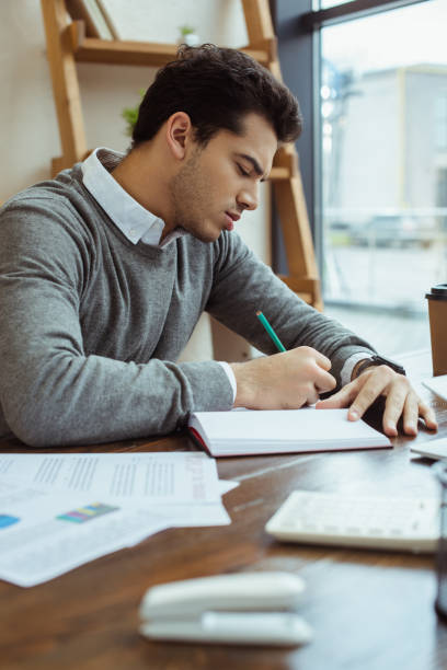 istock Selective focus of businessman writing in notebook at table in office 1218526516