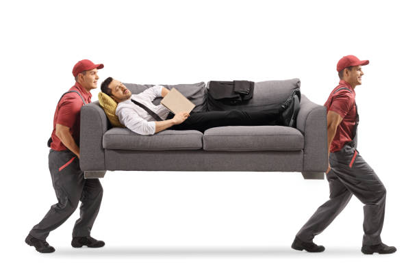 istock Businessman sleeping on a sofa with a book while movers carrying the sofa 1218530578