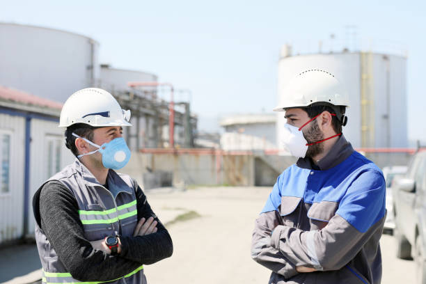 arbeiter sprechen mit schutzmasken für coronavirus (covid-19) epidemie im baubereich. beim menschen verursachen coronaviren infektionen der atemwege, die von leicht bis tödlich reichen können. - safety meeting construction site construction stock-fotos und bilder