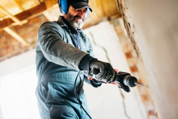 istock Mature worker demolishing wall with drill at house 1218534625