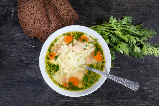 istock Chicken noodle soup in bowl with spoon, bread, top view 1218537364