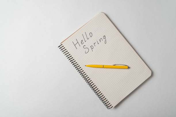 istock Hello spring handwriting notice. Top view of Notepad and pen on white background. 1218539834