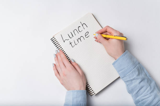 istock Female hands writing words LUNCH TIME on white background. 1218539870