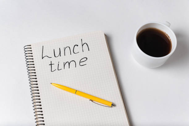 istock Notebook with LUNCH TIME inscription. Cup of coffee and pen white background 1218539889