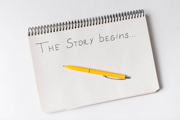istock Notepad with words THE STORY BEGINS. Top view of Notebook and pen. 1218539964