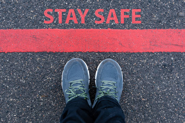 istock man in sneakers standing next to a red line with text STAY SAFE 1218540258